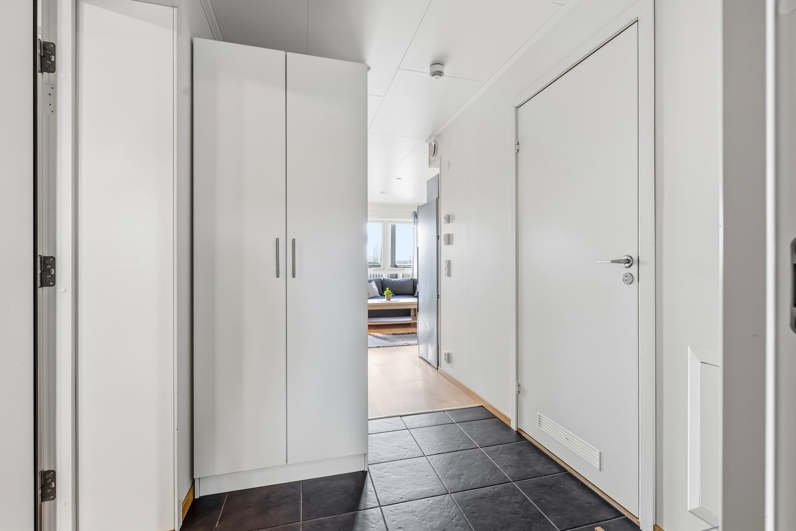 Man ønskes velkommen inn i en romslig entré som er praktisk innredet med flislagt gulv og god garderobeplass som gir godt med lagringsplass for yttertøy og sko. Galleribilde