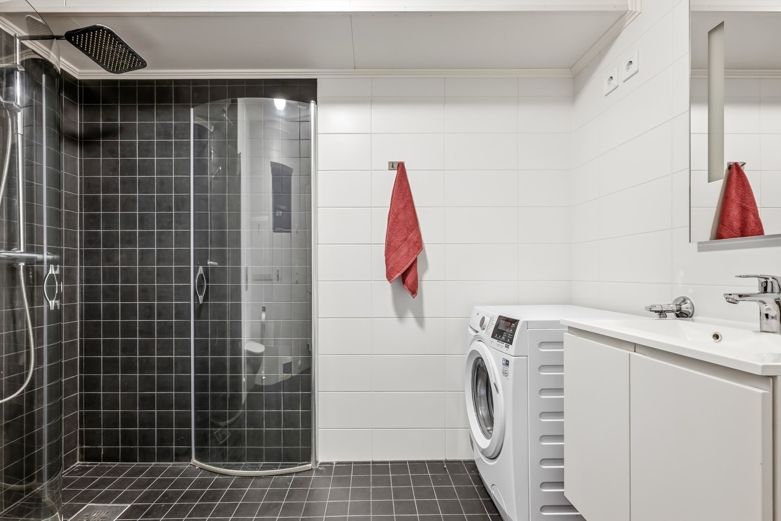 Badet er tidløst innredet med grå fliser på gulvet og i dusjsonen og ellers hvite fliser på vegg. I gulvet har man også varmekabler for ekstra komfort. Galleribilde