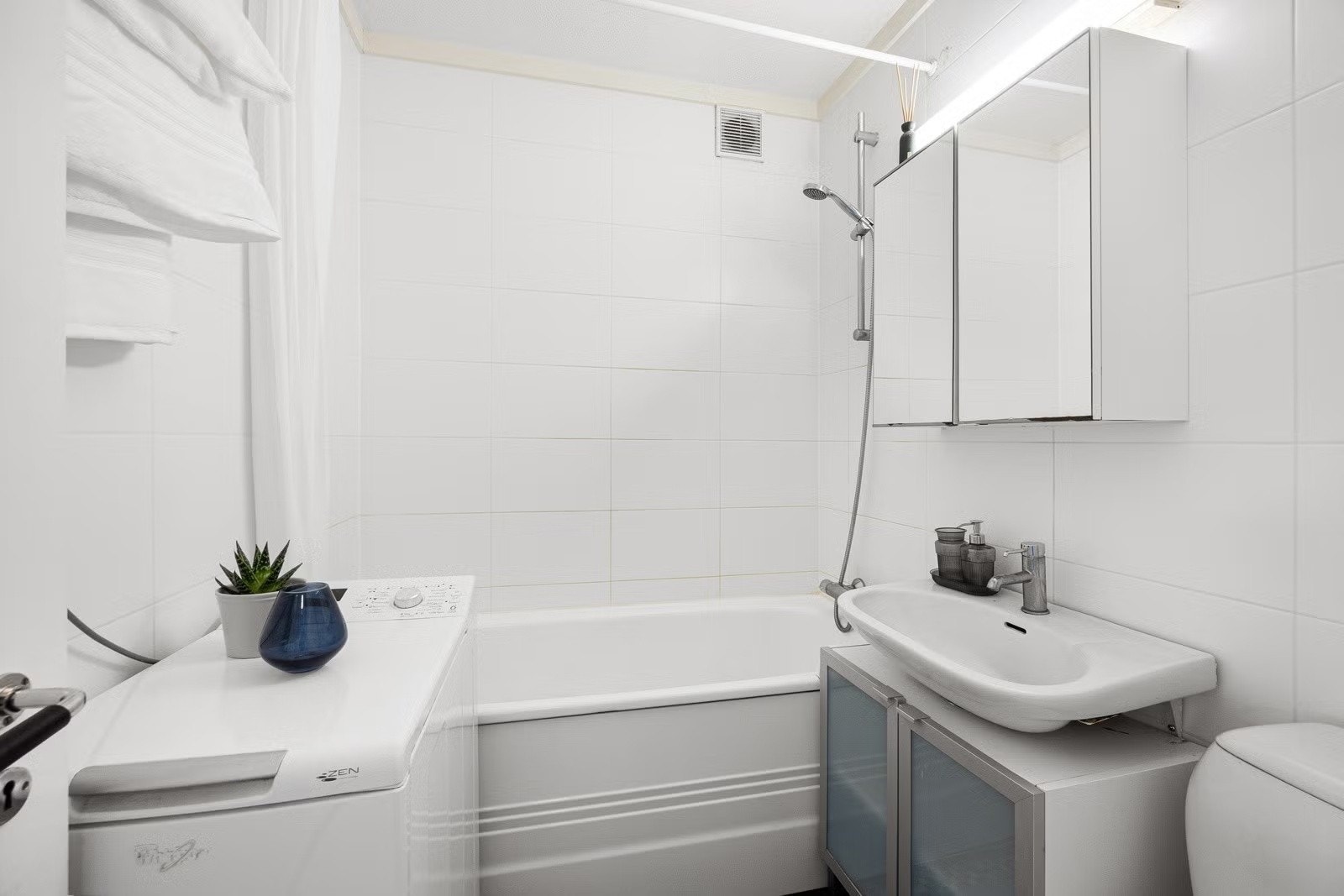 Flislagt bad med badekar og vaskemaskin. Galleribilde