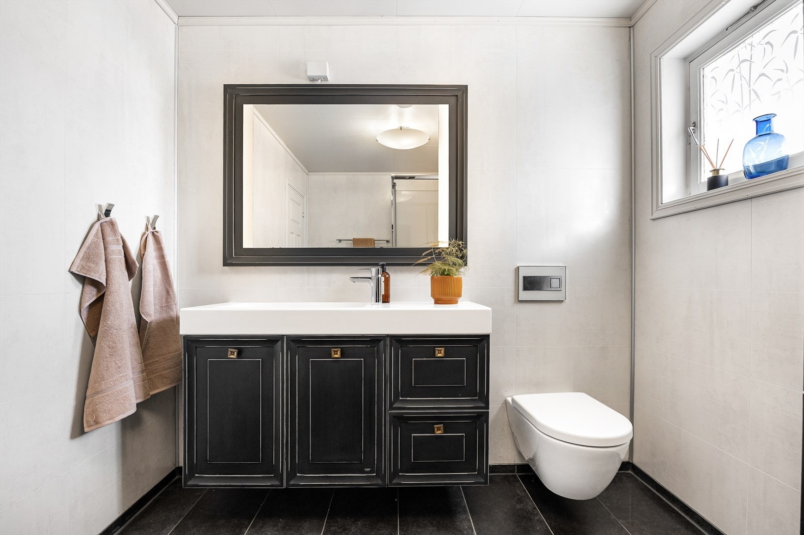 Innredningen består av et sort servantskap i et stilrent, tøft design, et dobbelt høyskap i samme stil og et stort, matchende speil over servanten. Galleribilde