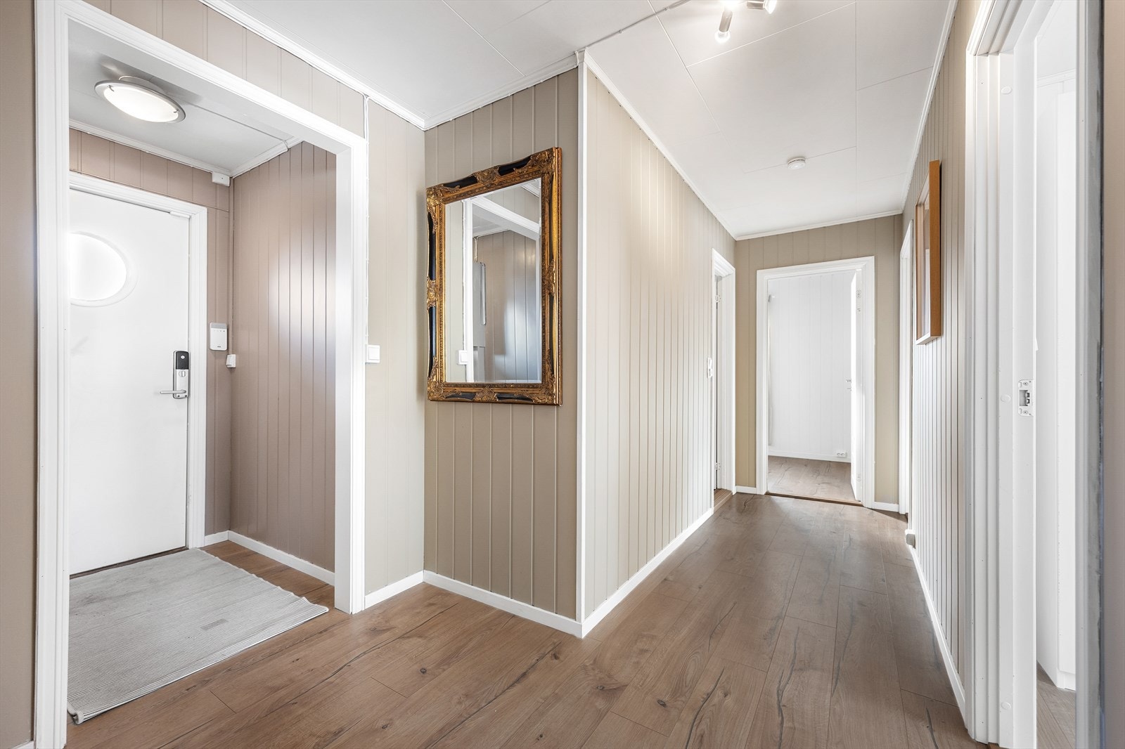 Vel inne har boligen en liten entré med videre adkomst til en større gang. På gulvet er det 1-stavs laminat og veggene er malt i en trendy farge. Galleribilde