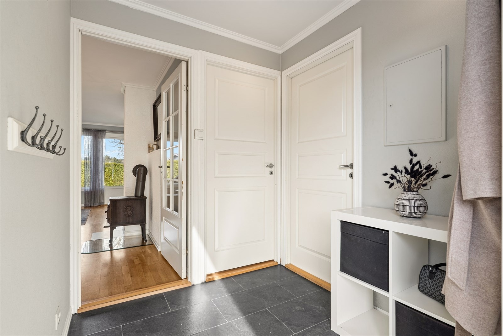 Velkommen inn i en lys og innbydende entré med praktisk oppbevaring og direkte adkomst til det åpne oppholdsrommet Galleribilde