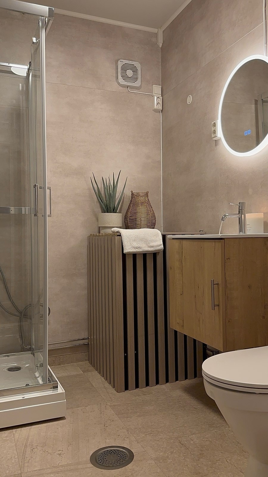 Badet er innredet med servant, speil med lys, toalett og dusjkabinett Galleribilde