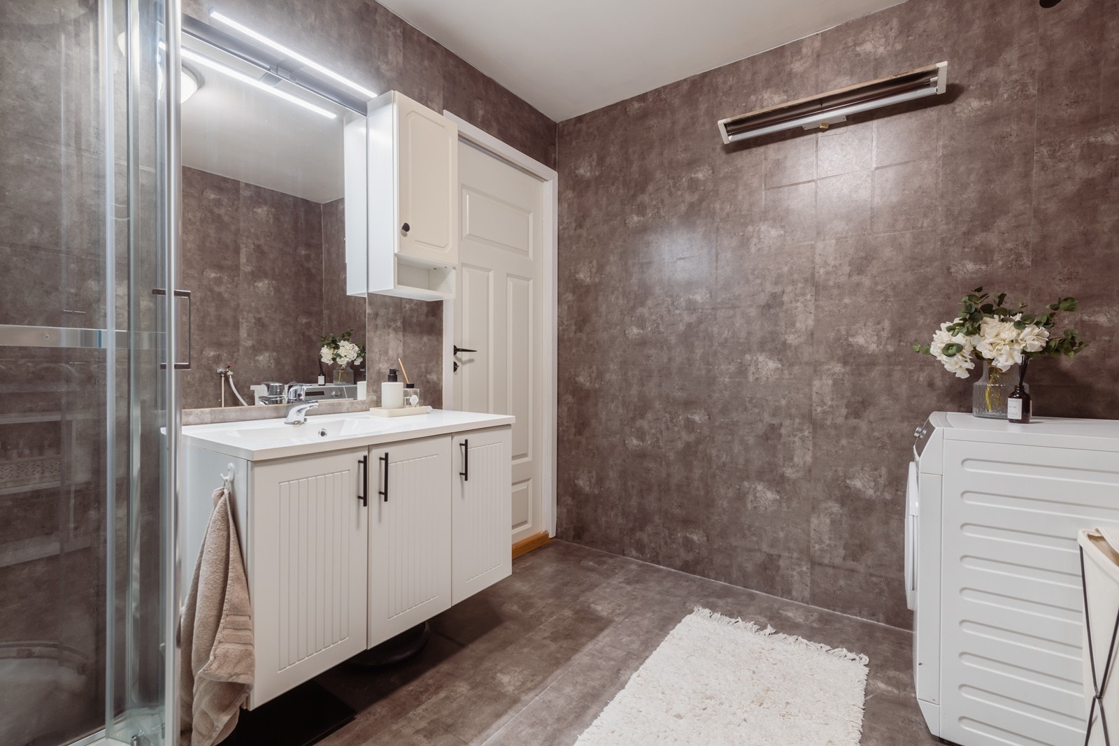 Badet er av god størrelse og innredet med nedfelt servant, dusjkabinett og opplegg for vaskemaskin Galleribilde