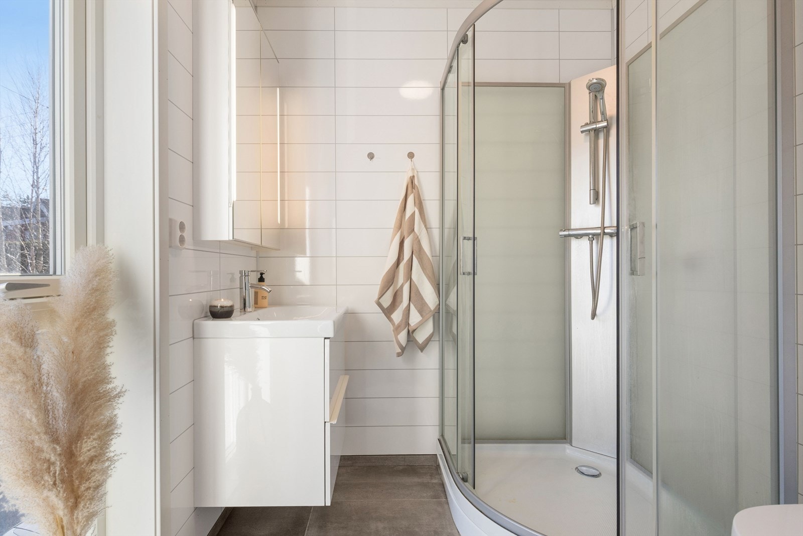 Badet har flislagt gulv med varmekabler, vegghengt toalett og dusjkabinett. Galleribilde