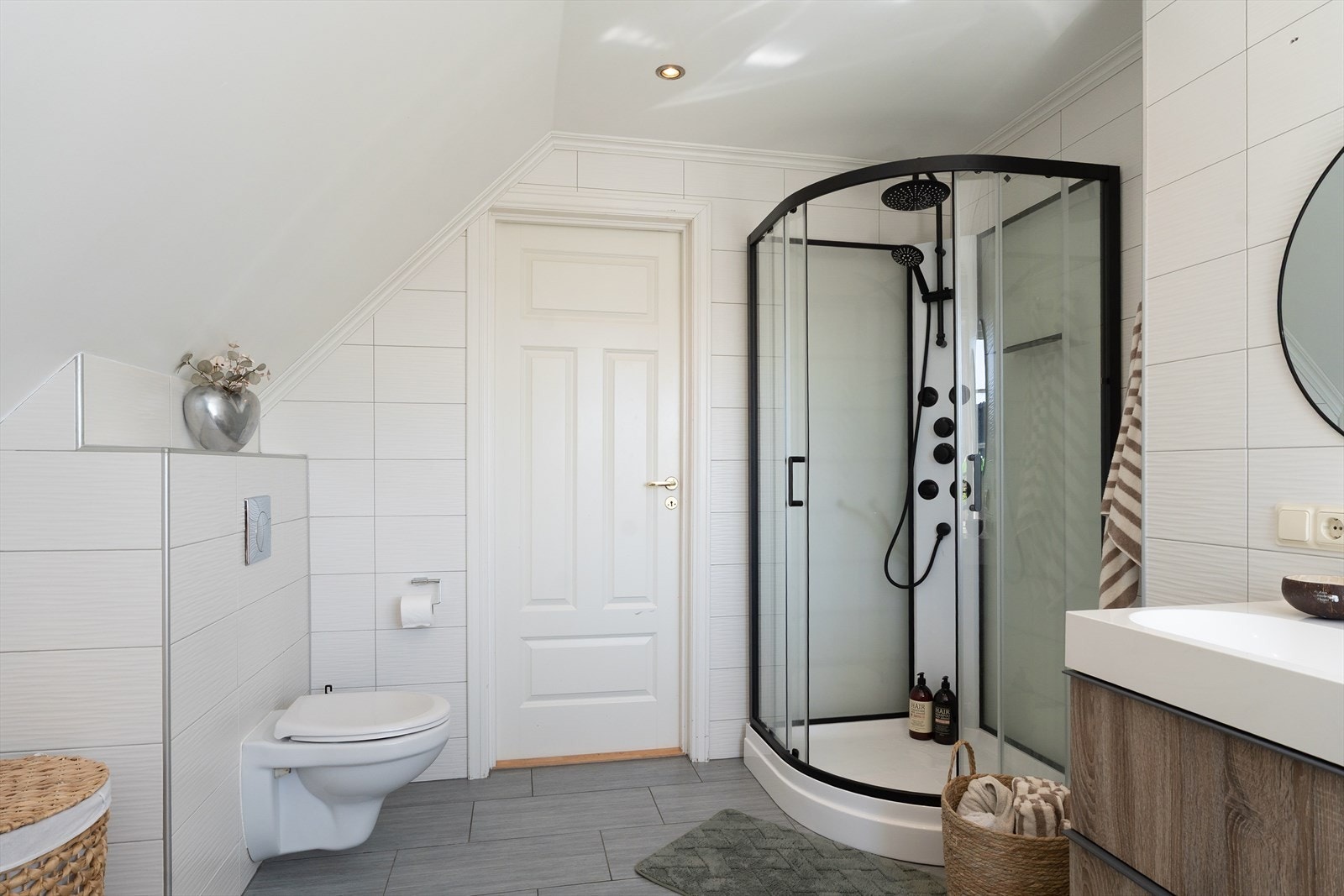 Badet inneholder baderomsinnredning med oppbevaringsplass og dobbel servant, dusjkabinett og veggmontert toalett. Galleribilde