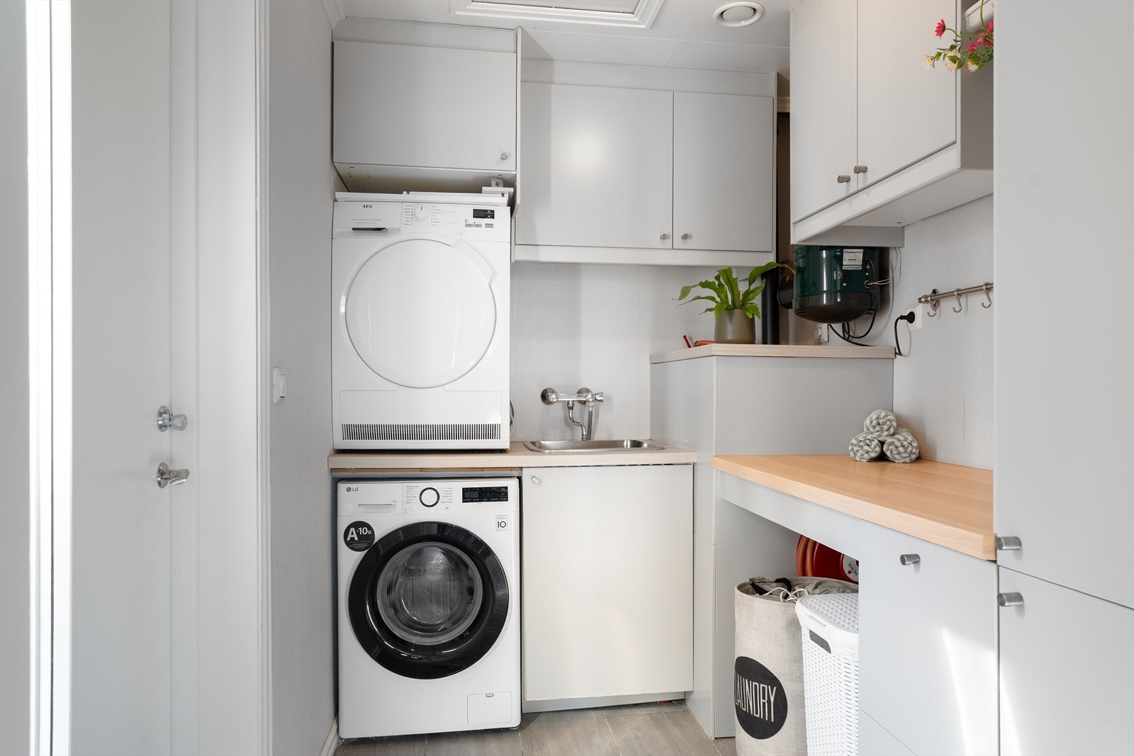 Vaskerom med bi-inngang. Rommet har praktisk vaskeromsinnredning med skap, benk, vask og plass/opplegg for vaskemaskin. Det er også plass til tørketrommel. Galleribilde