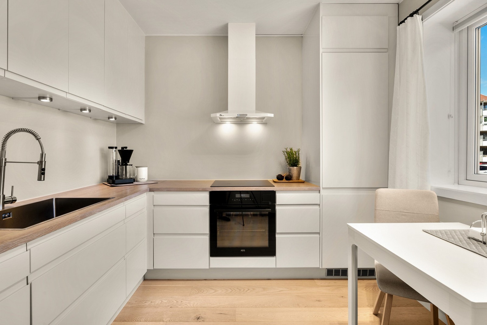 Tidløst og pent Norema-kjøkken fra 2019 med laminat benkeplate og downlights under overskap. Galleribilde