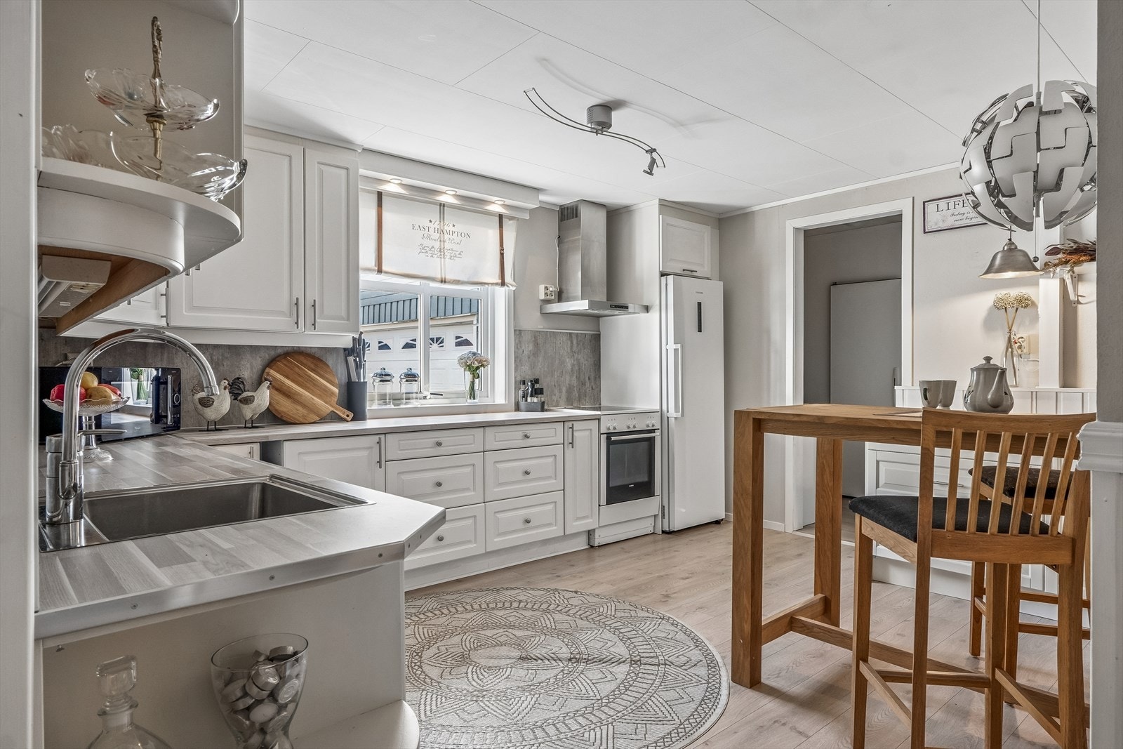 Kjøkkenet har innredning med profilerte fronter, benkeplaten er av laminat og plater type kitchenboard mellom benkeplate og overskap. Galleribilde