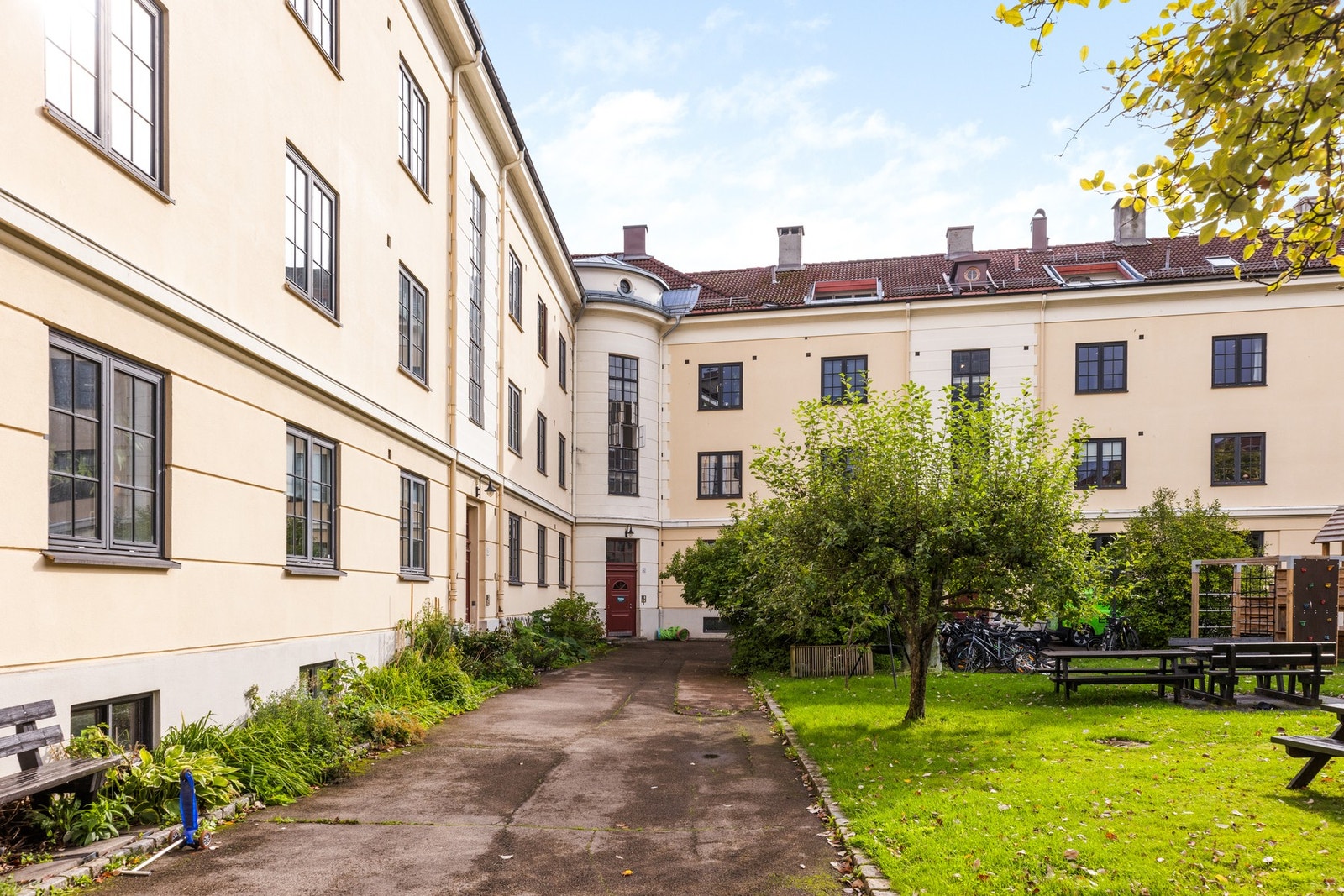 Innenfor gårdens port er det en stor, frodig felleshage som er pent opparbeidet med plen, beplantning, grill og sittegrupper. Galleribilde
