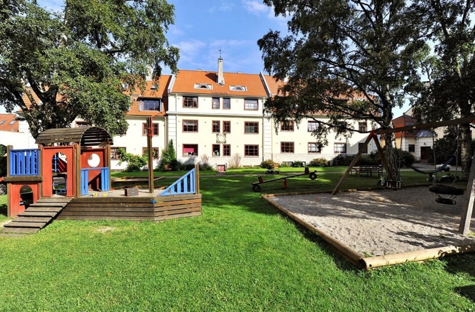 Idyllisk og rolig bakgård med flere sittegrupper, grill, lekeplass, og frodige forhager med møblering og beplantning Galleribilde
