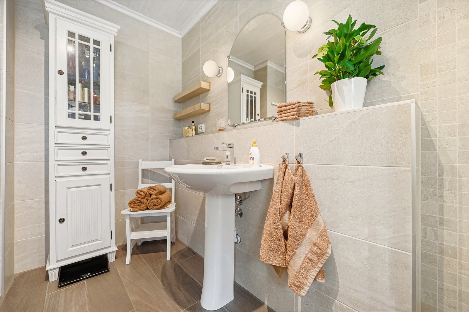 Lyst bad med servant, speil, vegghyller og skap. Galleribilde