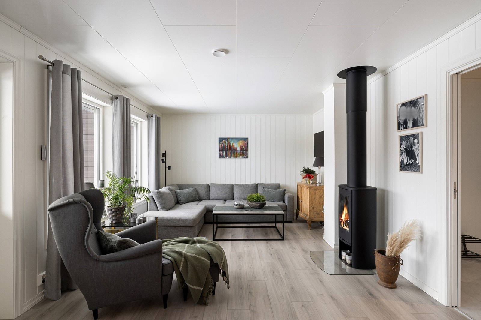 Store vindusflater gir rikelig med naturlig lys, og rommet har god plass til både sofagruppe og spisebord. Galleribilde