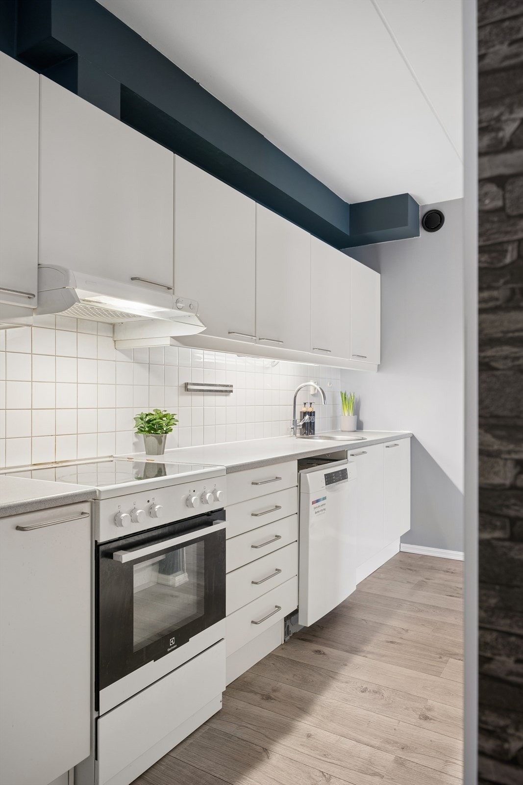 Klassisk kjøkken med frittstående hvitevarer og laminert benkeplate. Flislagt bakvegg og opplegg for oppvaskmaskin. Galleribilde