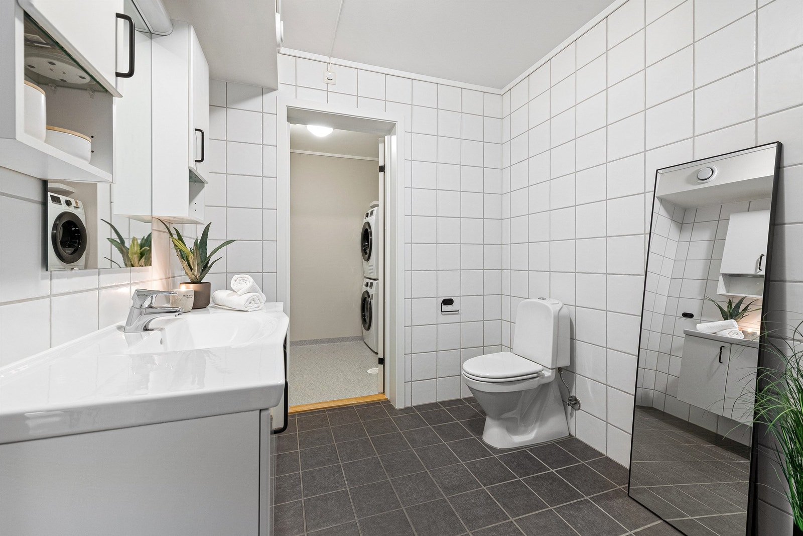 Badet har servantinnredning, gulvstående toalett og adkomst til et praktisk vaskerom. Galleribilde