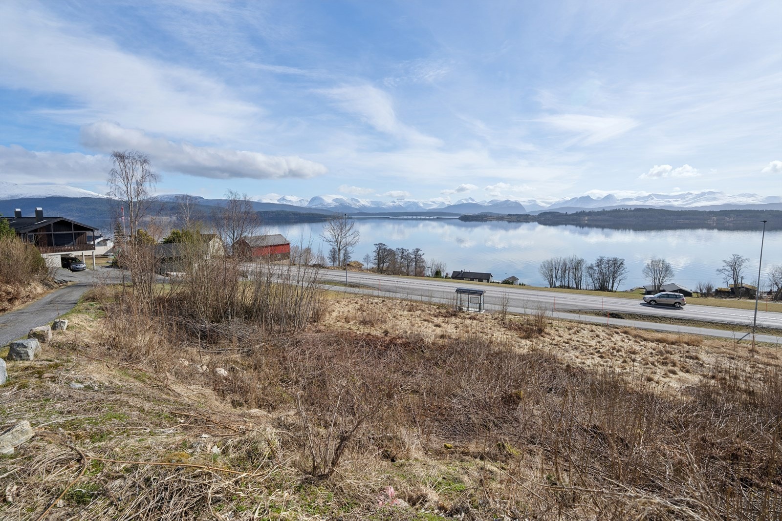 Her ligger tomten høyt og fritt, med en vidstrakt utsikt over fjorden og de snødekte fjellene i horisonten. Galleribilde