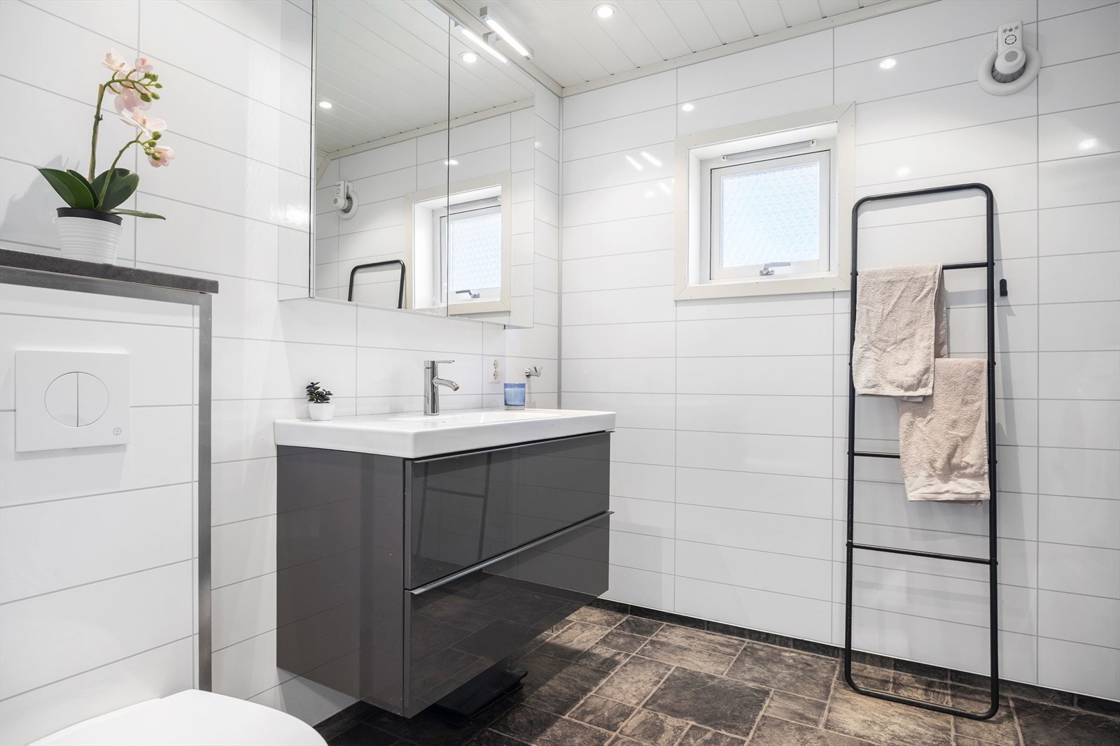 Badet med vegghengt toalett, innredning med skuffer og overskap med speilfronter, samt dusjkabinett. Galleribilde