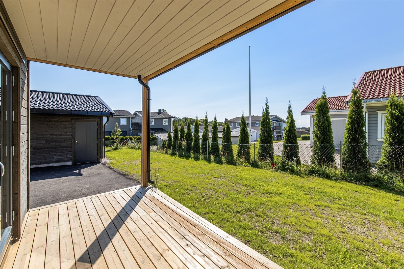Hagen er plensatt. Overbygget terrasse og hekk mot nabo Galleribilde