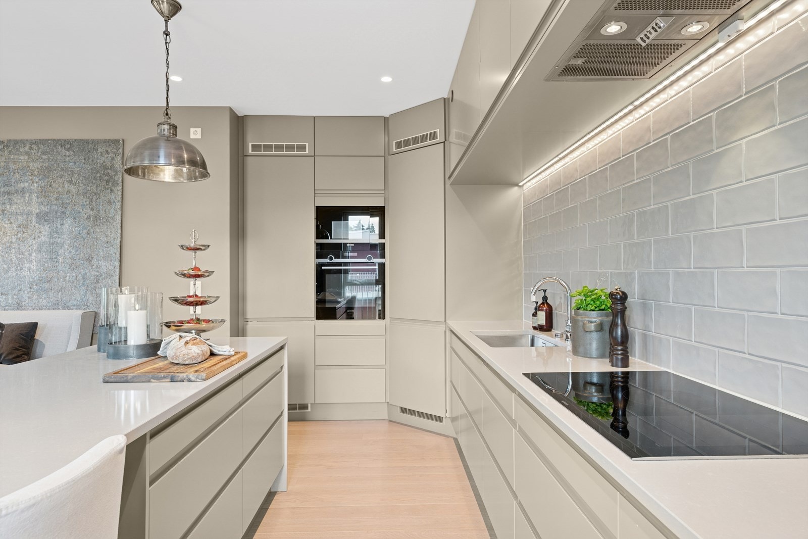 Kjøkkeninnredningen har en moderne stil med glatte fronter og integrerte håndtak. Integrerte hvitevarer med bl.a. 80cm induksjonstopp, kjølehjørne, fryseskap, stekeovn, mikrobølgeovn og oppvaskmaskin. Galleribilde