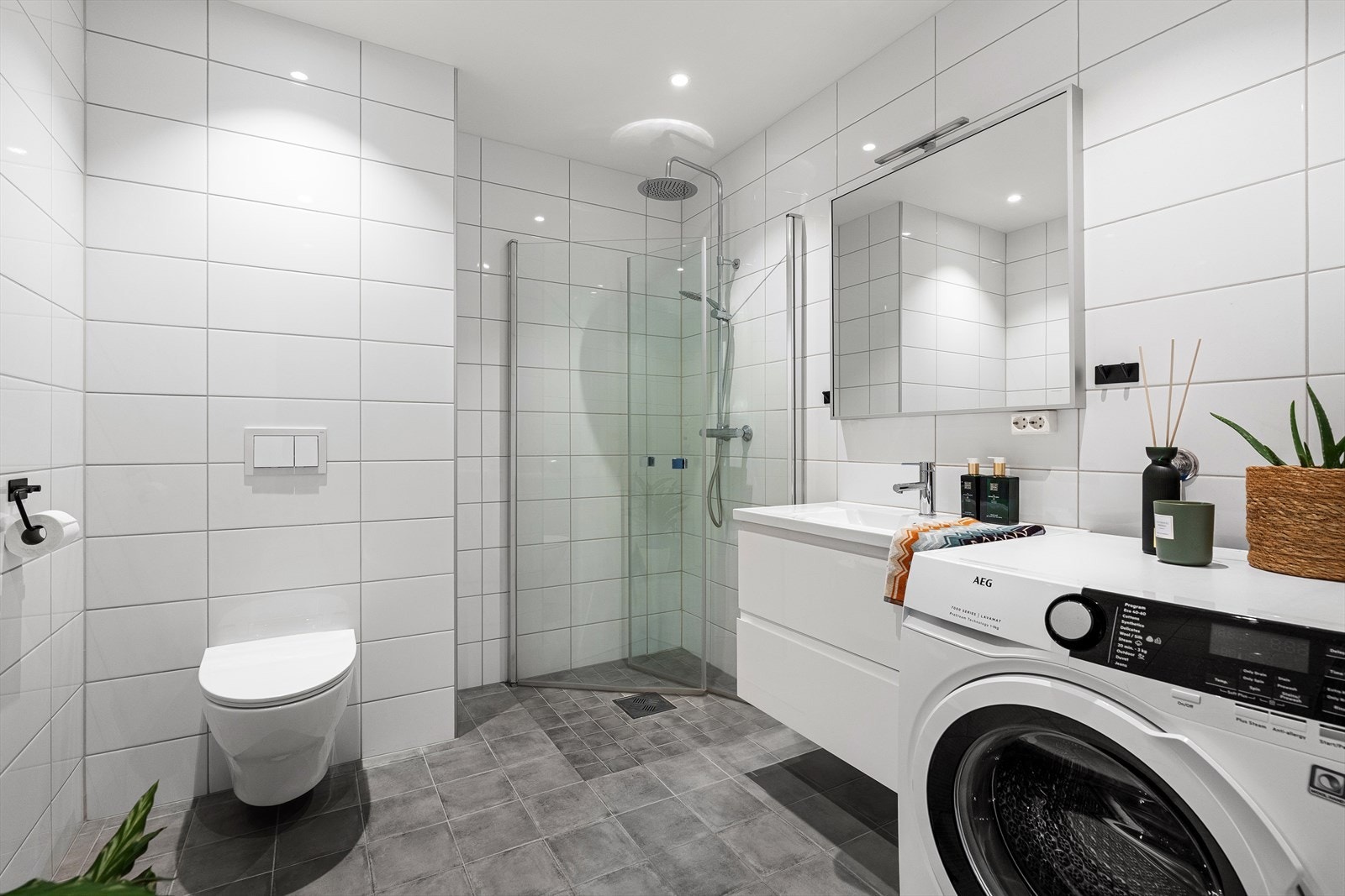 Badet er helfliset med vannbåren gulvvarme. Det inneholder alt du behøver som innfellbare dusjdører med regndusj, vegghengt toalett, baderomsinnredning med speil over, samt plass og opplegg for vaskemaskin/tørketrommel. Galleribilde