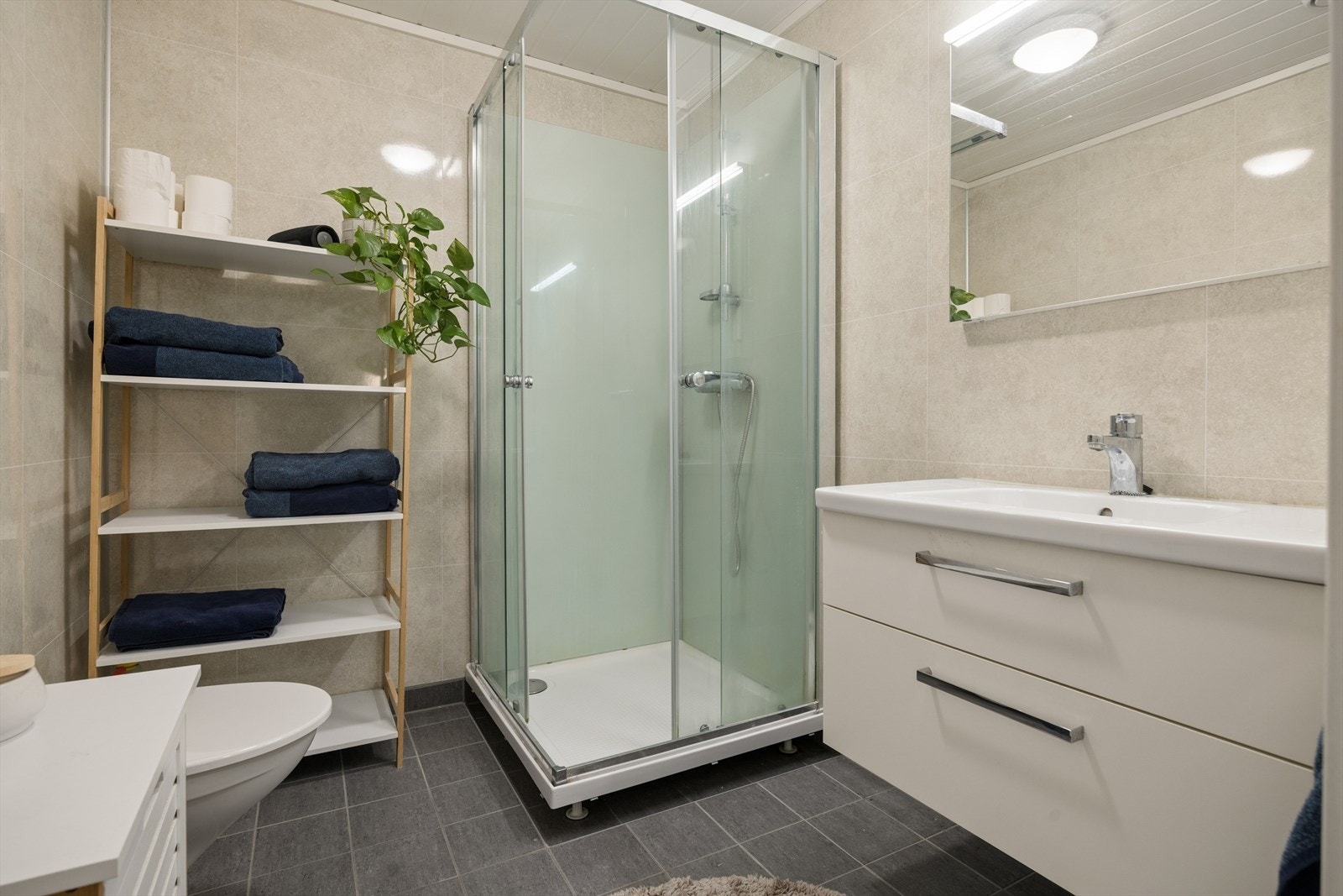 Pent bad på 4,2m² utstyrt med innredning med nedfelt servant, dusjkabinett og toalett. Galleribilde