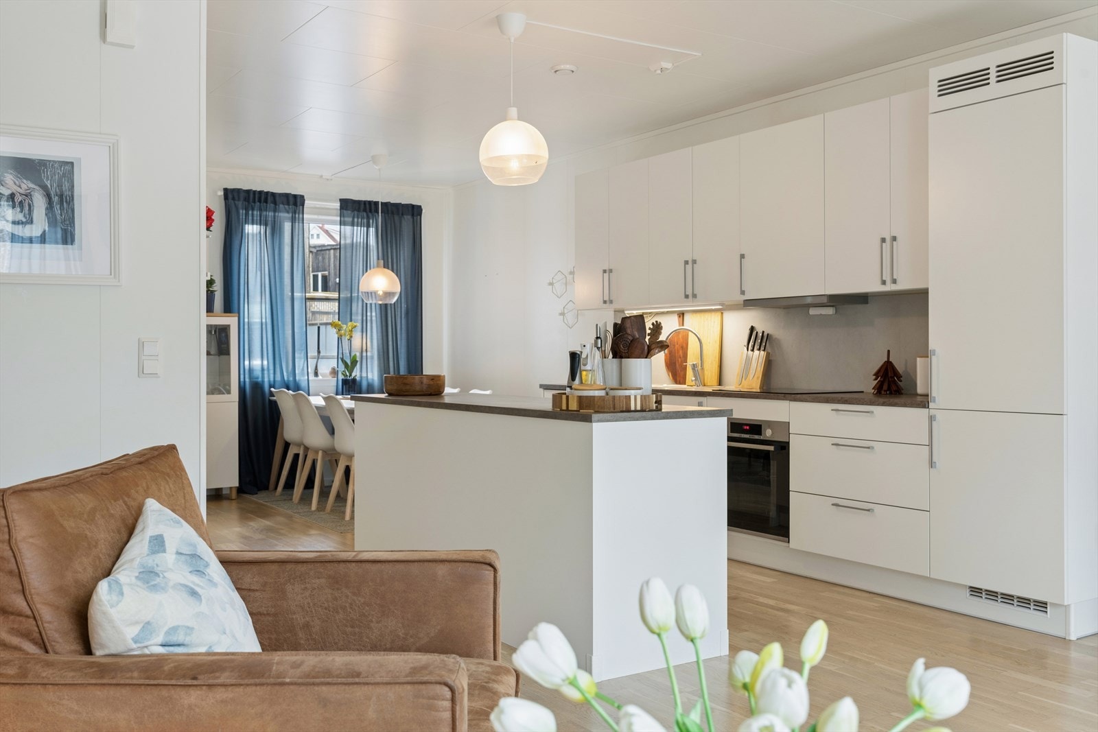 Stilrent kjøkken med hvite fronter og mørkere benkeplate. Galleribilde