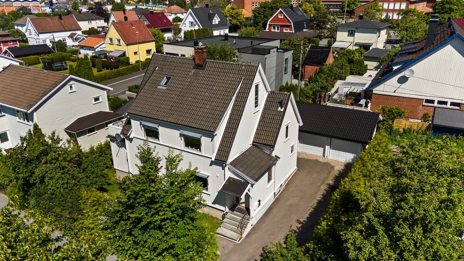 Fasade og området sett i fra luften. Tomten er opparbeidet med grøntarealer og innkjørsel Galleribilde