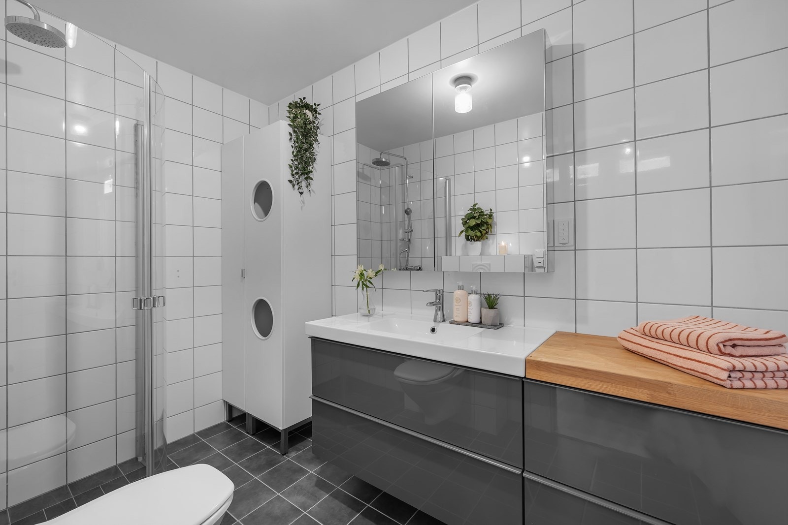 Stor og delikat innredet bad med fliser på gulv og vegger. Stor innredning med gode lagringsmuligheter. Galleribilde