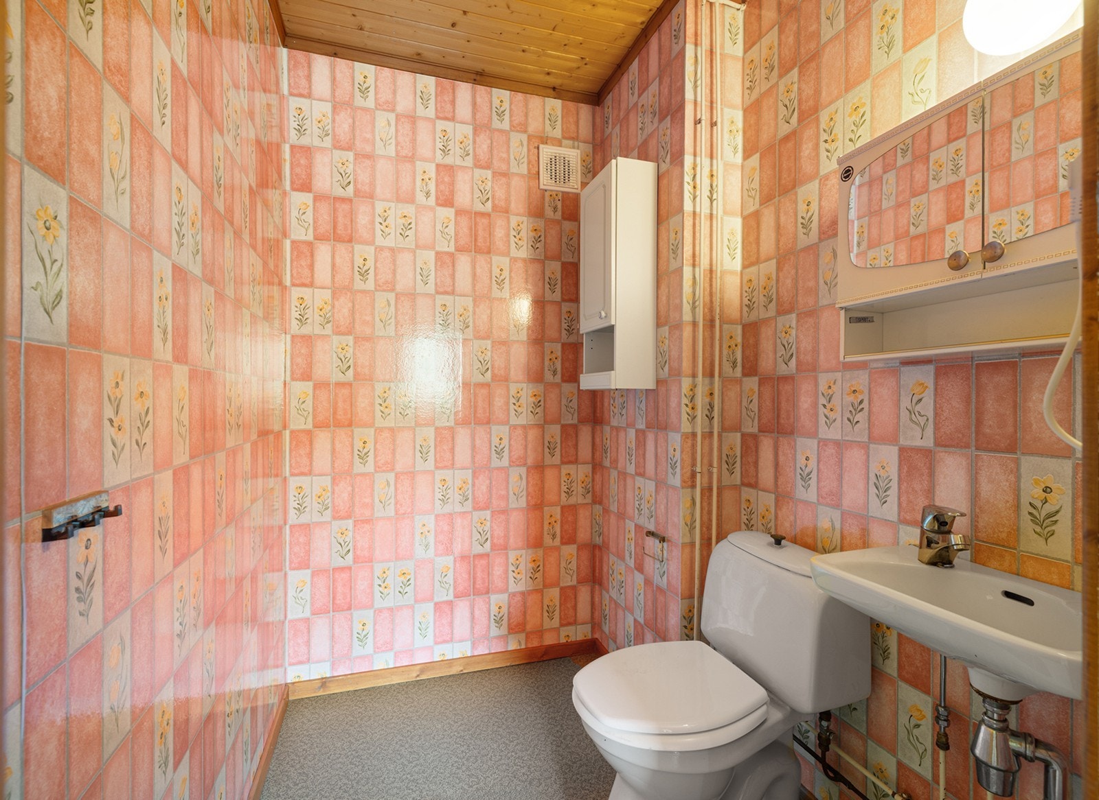 Toalettrom med servant, speil og toalett. Rommet har enkel standard. Galleribilde