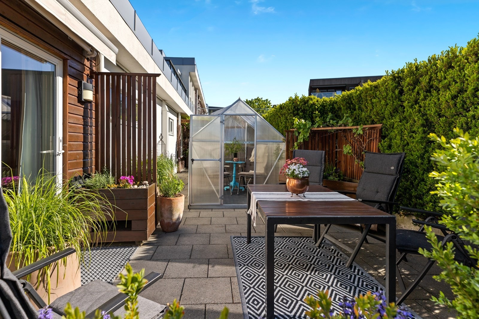 Uteplassen er pent opparbeidet med beplantning og inkluderer to små drivhus for den med grønne fingre. Galleribilde