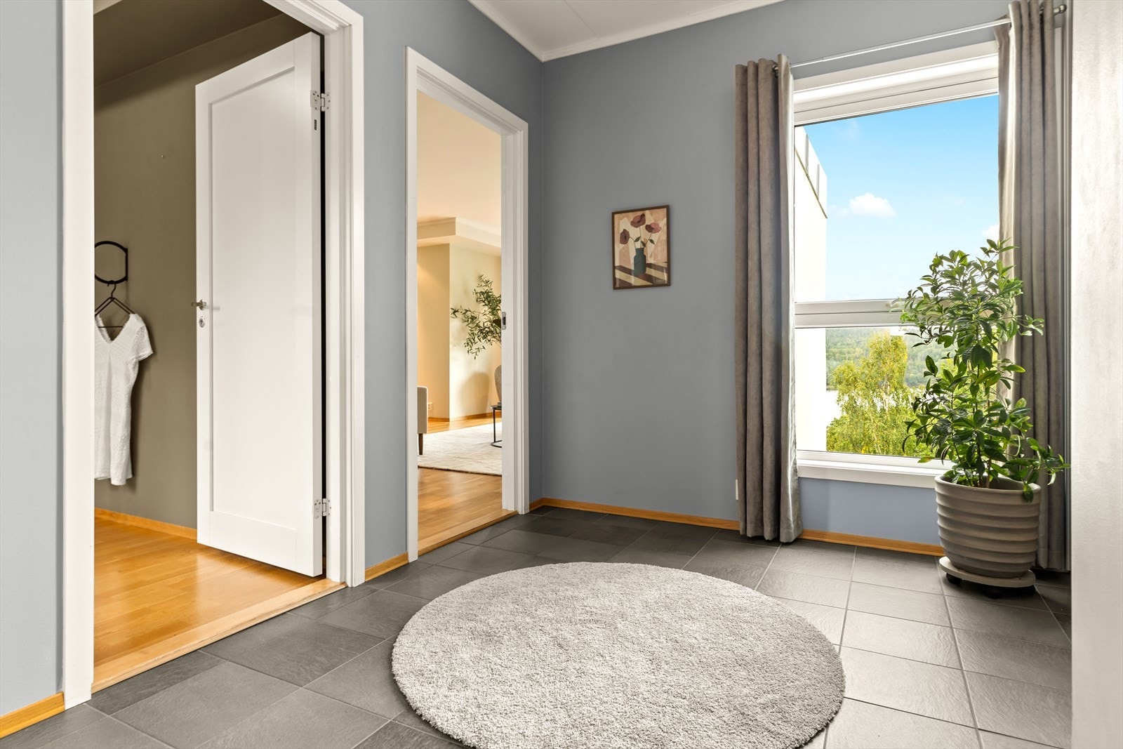Romslig hall med flislagt gulv, skyvedørsgarderobe og porttelefon. Ytterdøren har kodelås fra Yale Doorman. Galleribilde