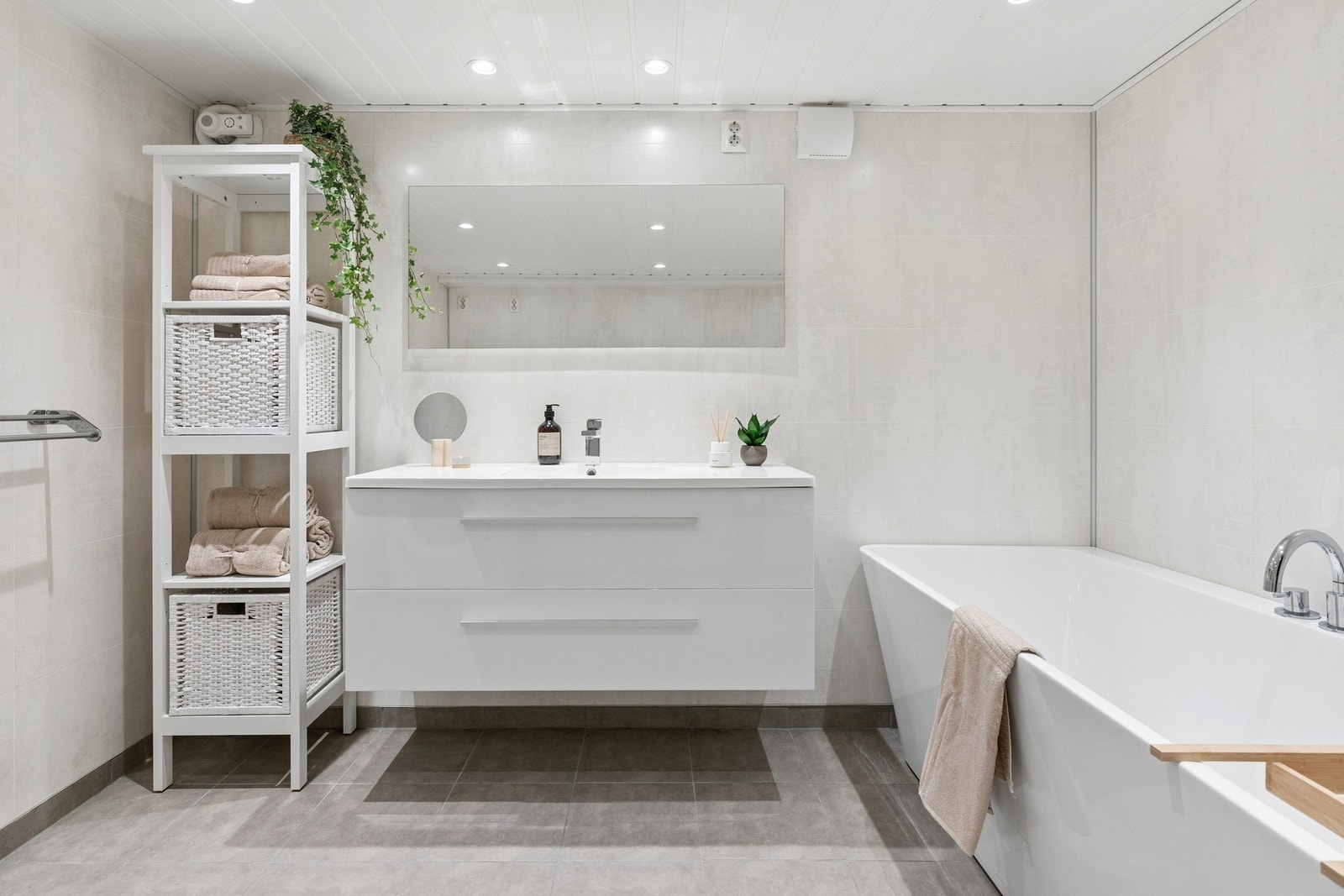 Baderommet er utstyrt med fliser på gulv og baderomsplater på vegger, hvit servantinnredning med skuffeseksjon, opplegg for vaskemaskin og innebygd/vegghengt toalett. Galleribilde