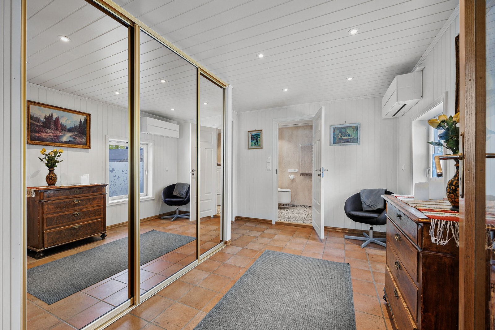 Lys og innbydende hall med keramiske fliser på gulv og smartpanel på vegger som gir et godt førsteinntrykk. Hallen har innebygd speil-skyvedørsgarderobe og pent lyssatt himling med downlights. Galleribilde