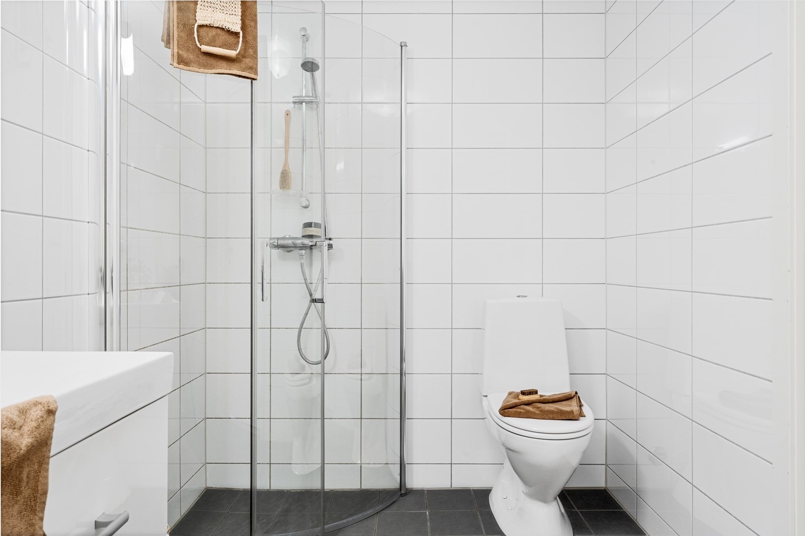 Badet er innredet med servant i møbel, speil, toalett, dusj medglassdører og opplegg for vaskemaskin. Galleribilde