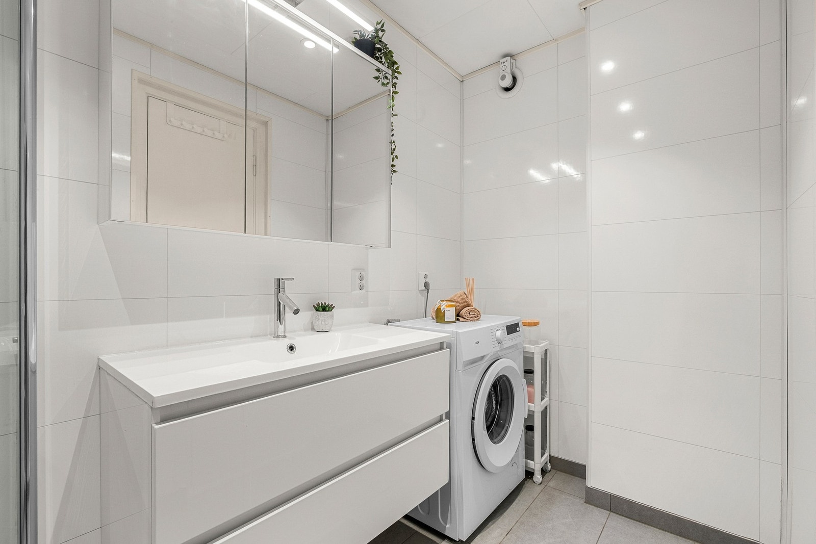 Badet er innredet med varme i gulv, servantinnredning, dusjhjørne med innfellbare glassdører og opplegg for vaskemaskin Galleribilde