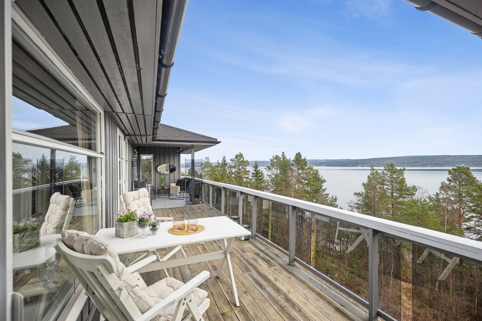 Stor og flott veranda med gode møbleringsmuligheter og en vidstrakt fjordutsikt. Her er alt lagt til rette for å tilbringe sommerhalvåret utendørs. Galleribilde
