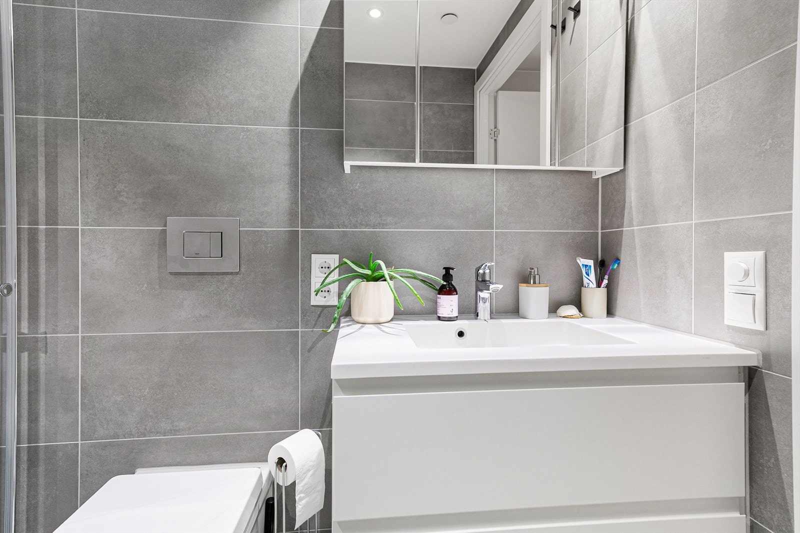 Innredningen på badet består av servant med skap, speilskap og vegghengt toalett. Galleribilde