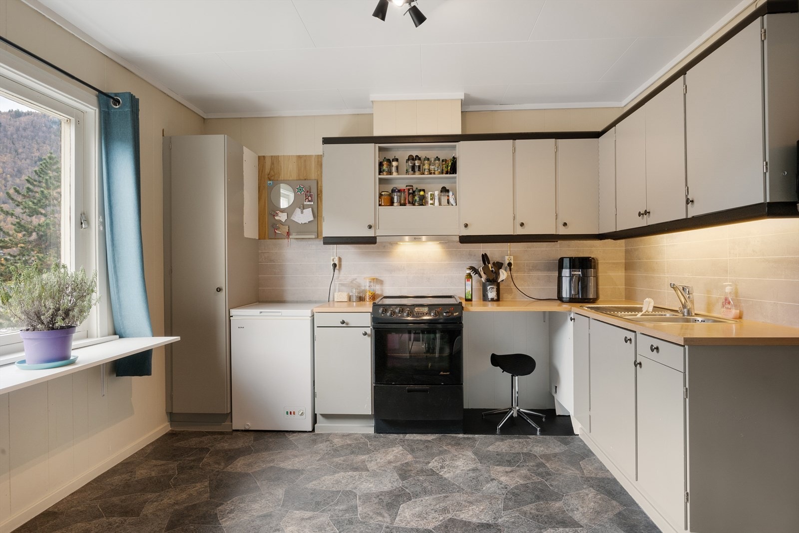 Kjøkkeninnredning har glatte fronter som er malt i en fin gråtone. Galleribilde