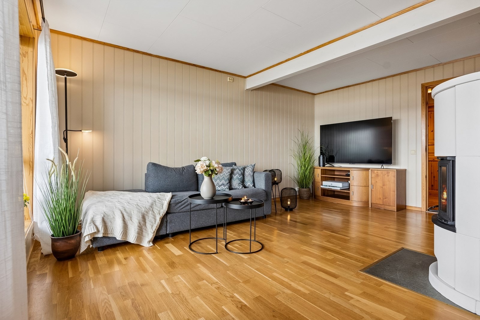 God plass til sofagruppe med tilhørende møblement. Det er lagt parkett på gulv og malte panelplater på vegger. Galleribilde