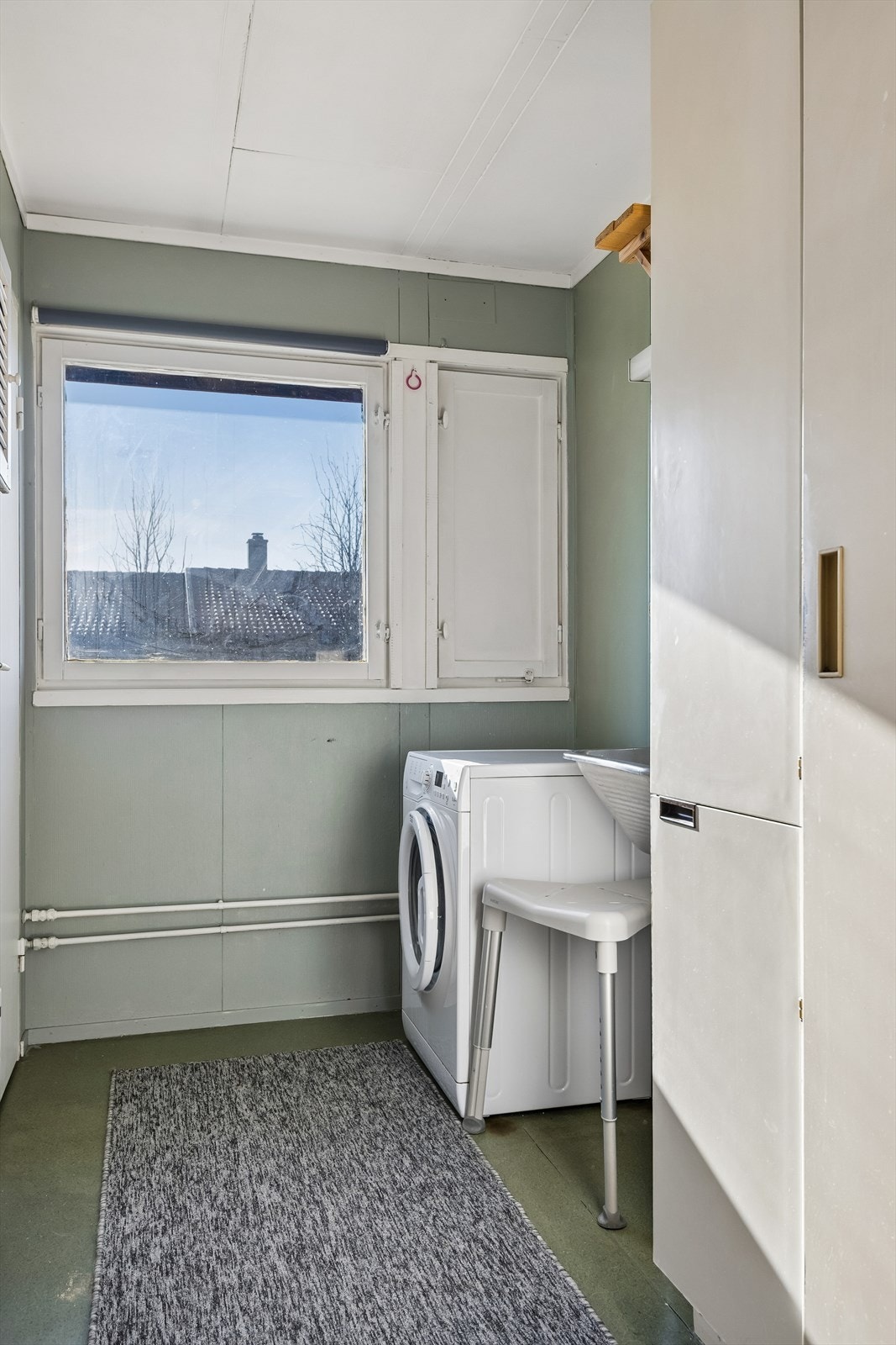 Praktisk vaskerom med utslagskum, tørkeskap og opplegg for vaskemaskin. Galleribilde