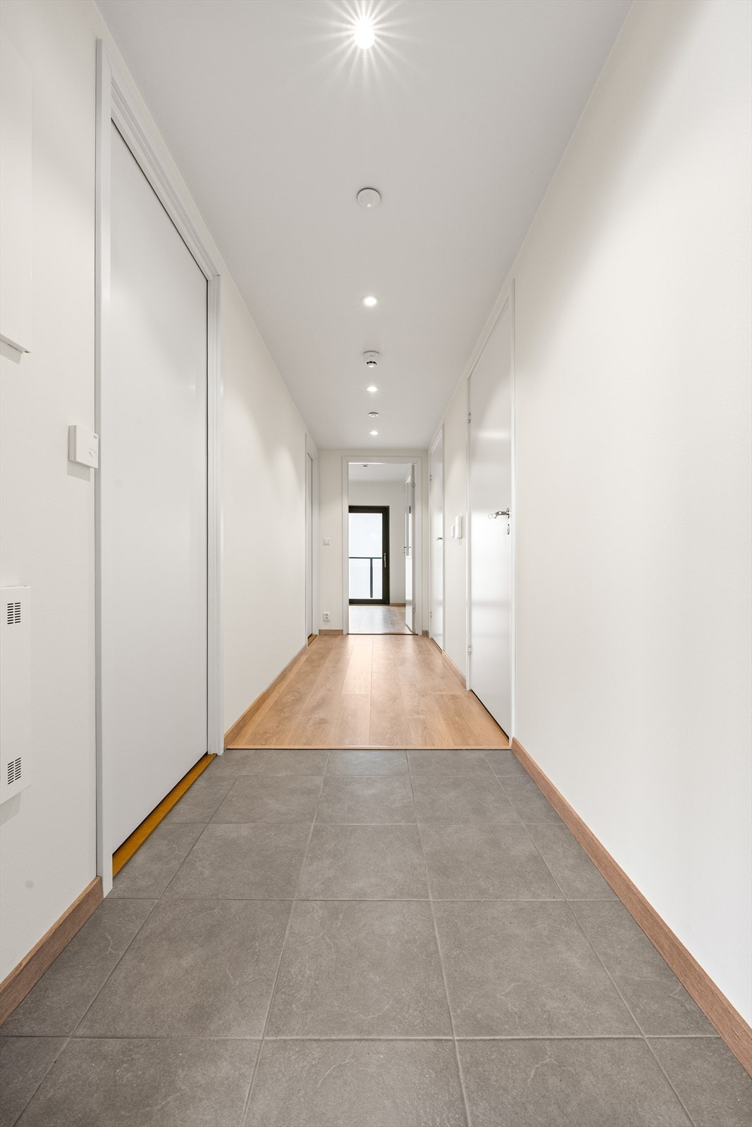 Den lange entréen har praktiske fliser og downlights i taket, og binder sammen rommene i leiligheten. Galleribilde