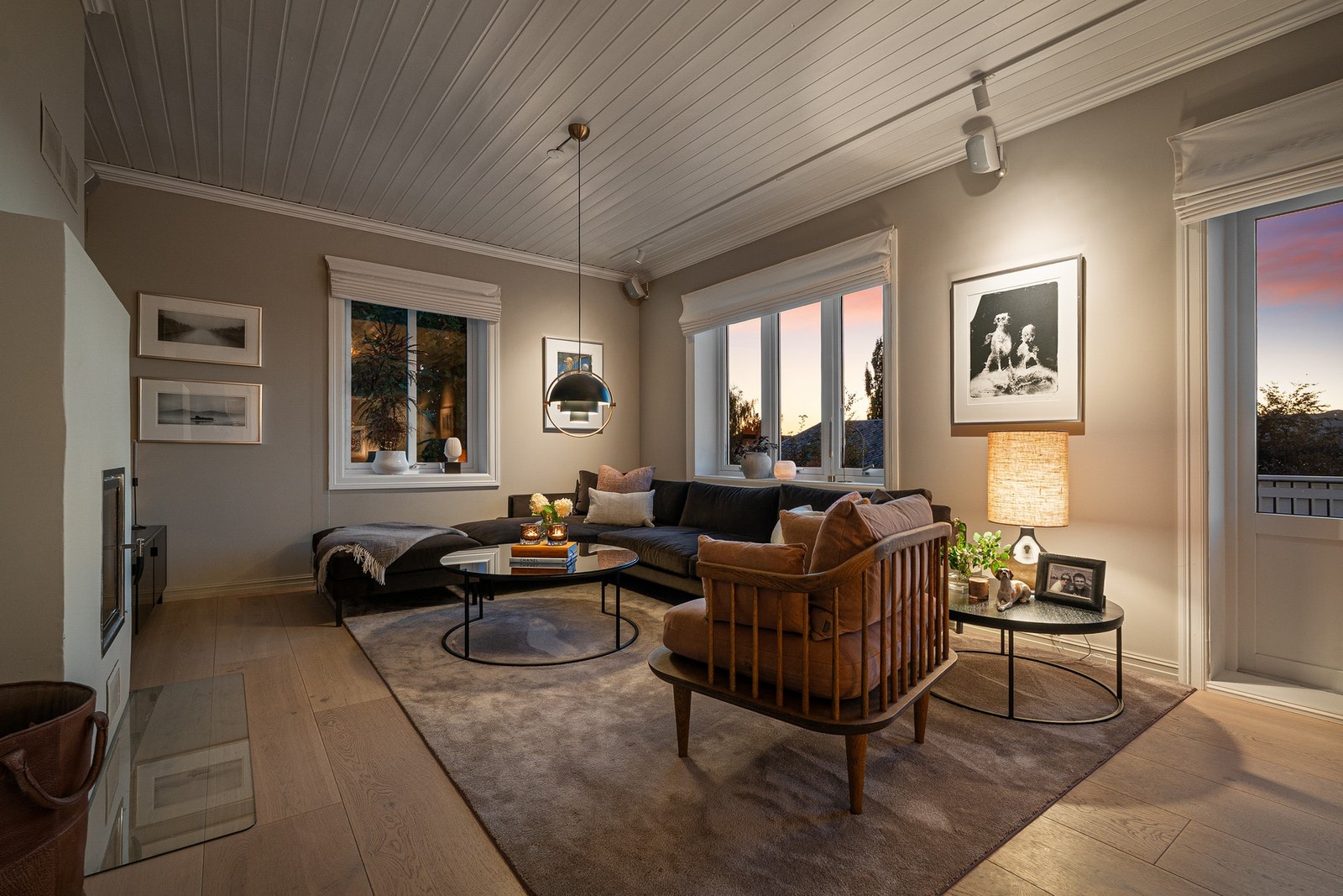 En koselig og gjennomført stue med peis som naturlig samlingspunkt og en rolig, hjemmekoselig følelse. Galleribilde