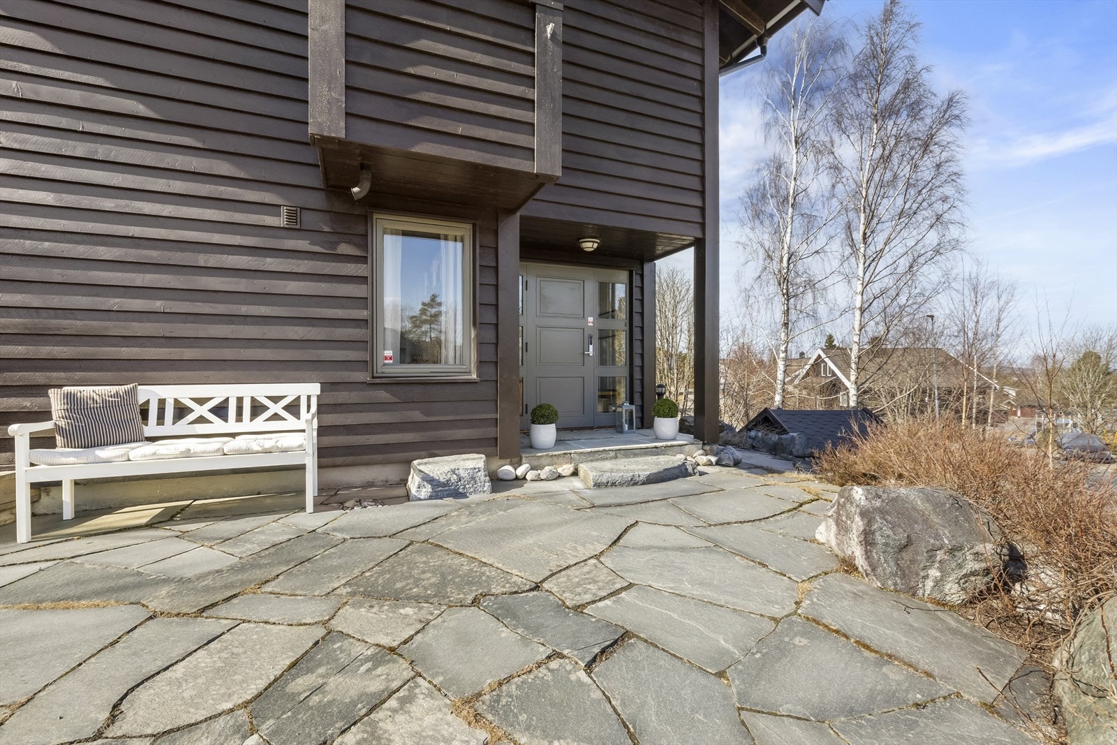 Innbydende inngangsparti med steinlagt platting og hyggelig sitteplass. Galleribilde
