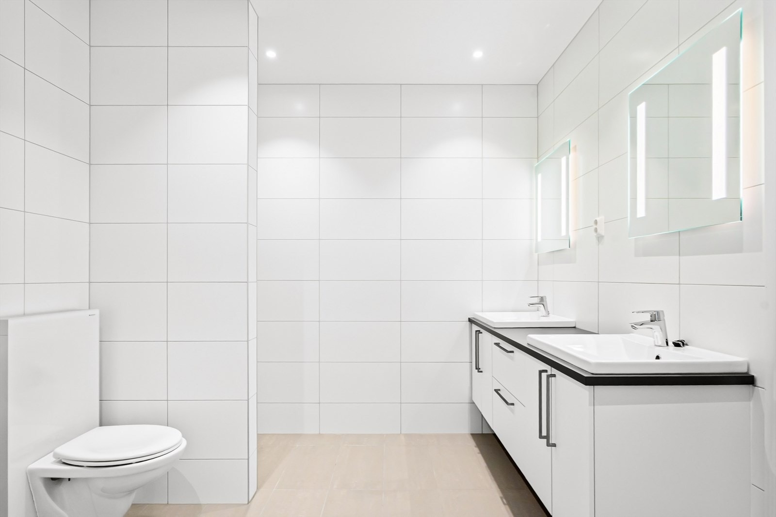 Badet er delikat med flislagte overflater, gulvvarme og downlights, samt innredning fra Sigdal med to servanter og speil med lys. Galleribilde