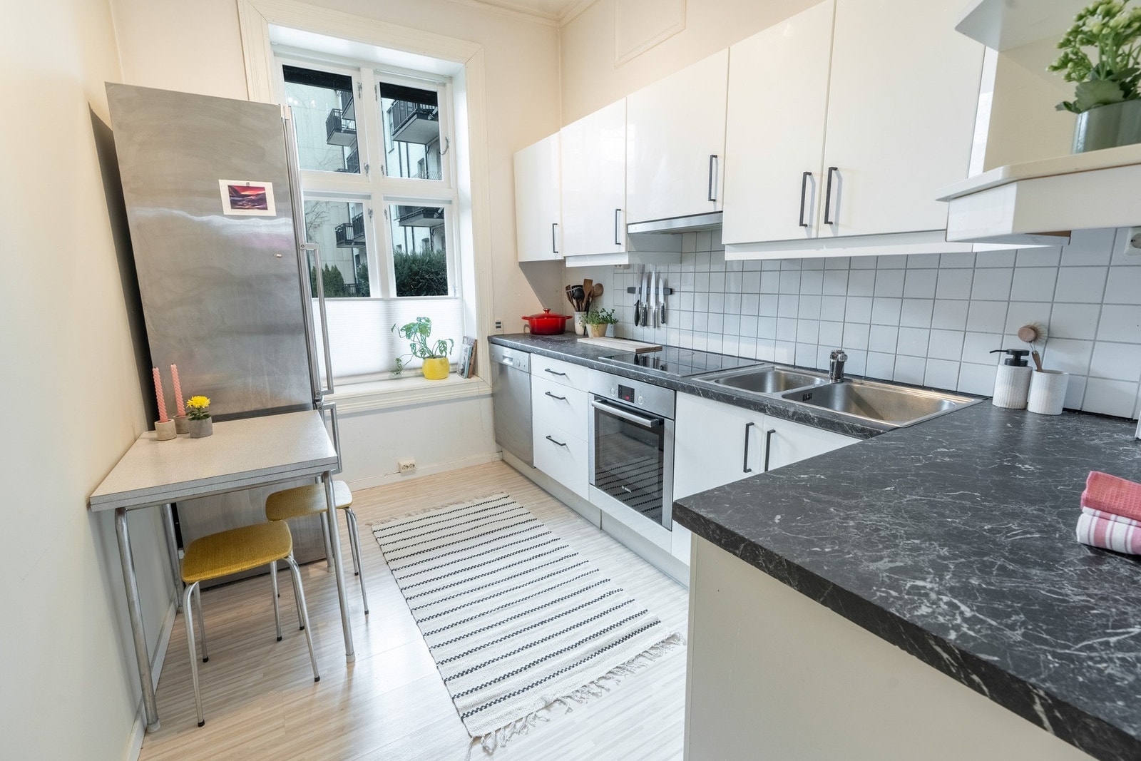 Lyst kjøkken med glatte fronter i hvit utførelse kombinert med benkeplate av laminat. Galleribilde