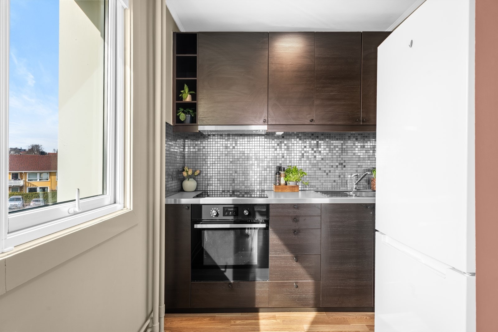 Veggen over benken er kledd med mosaikkfliser. Innredningen er utstyrt med keramisk platetopp, stekeovn og en kjøkkenventilator med kullfilter. Galleribilde