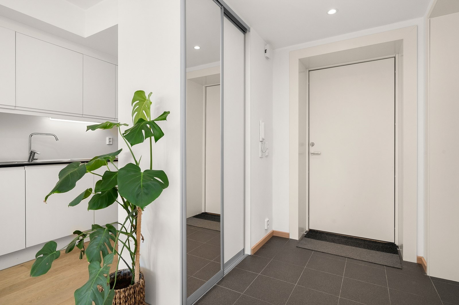 Praktisk entré med flis på gulv med behagelig gulvvarme. Det er downlights i himling og skyvedørsgarderobe med innredning og speilfront Galleribilde