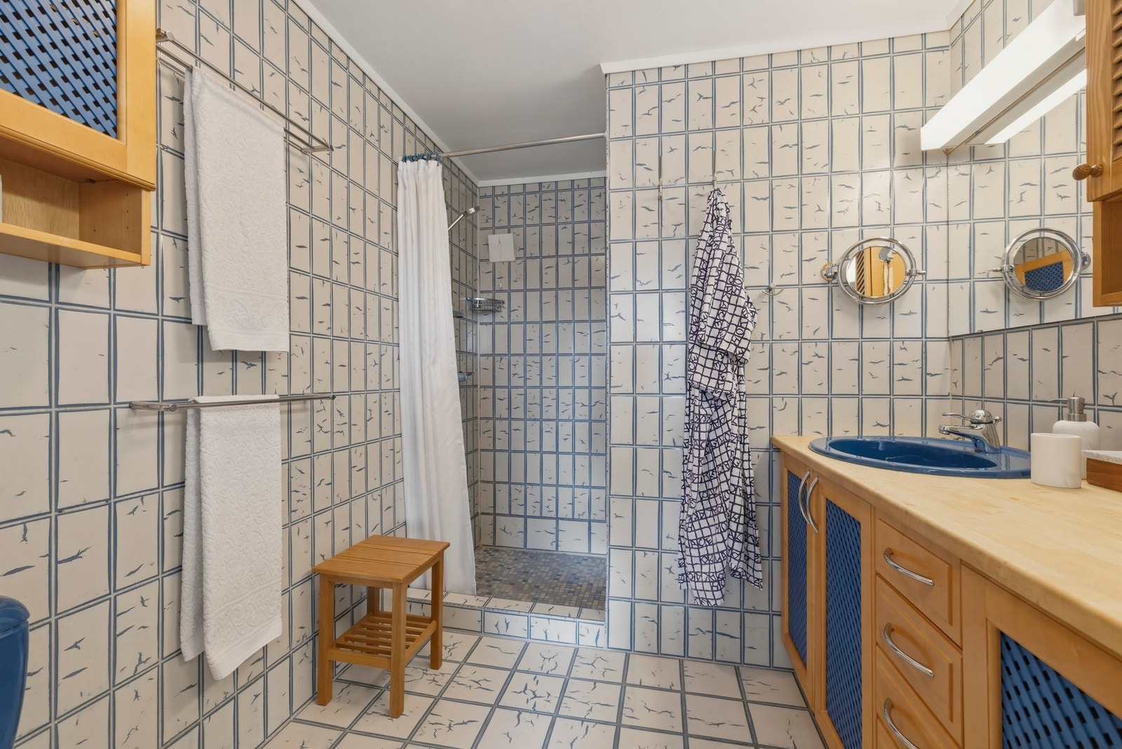 Romslig bad med flislagte vegger og gulv, med gulvvarme. Badet er pent og flisene er ikoniske, men fra byggeår og modent for revnovering. Galleribilde