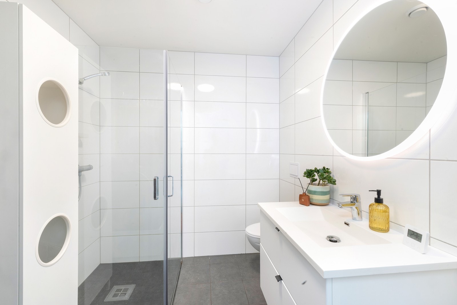 Badet er flislagt og har innredning med servant med skuffer og speil Galleribilde