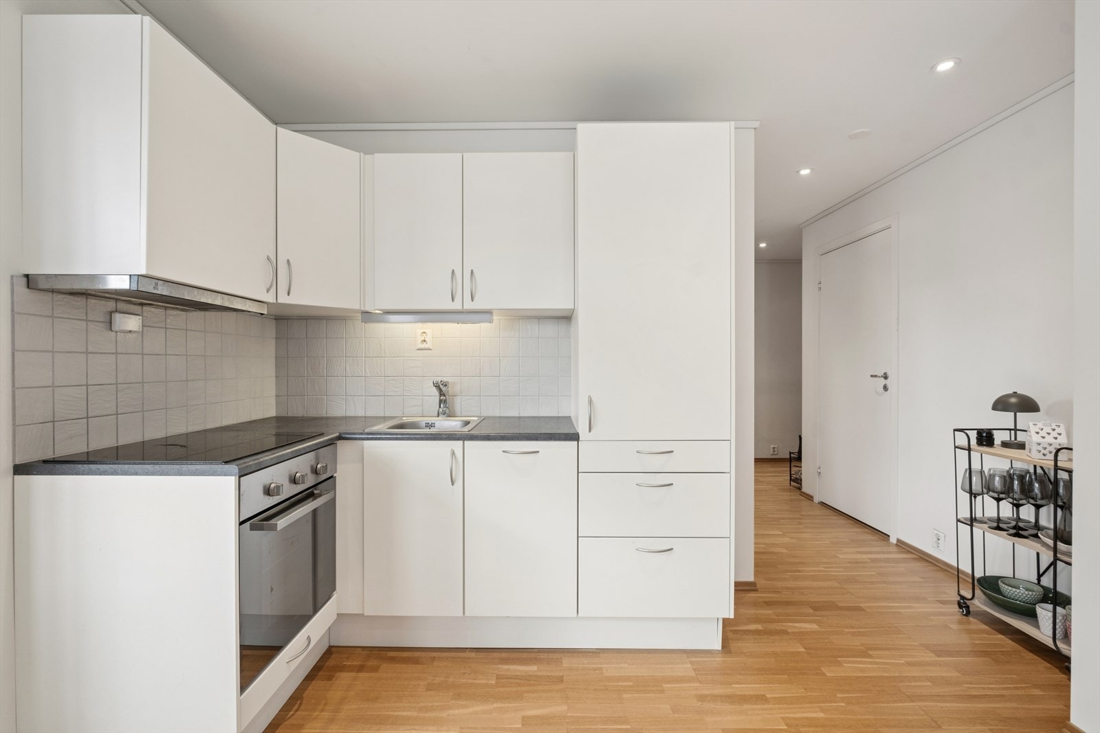 Kjøkkenet er utstyrt med laminatbenkeplate, flislagt felt over benken og ventilator med kullfilter. Galleribilde